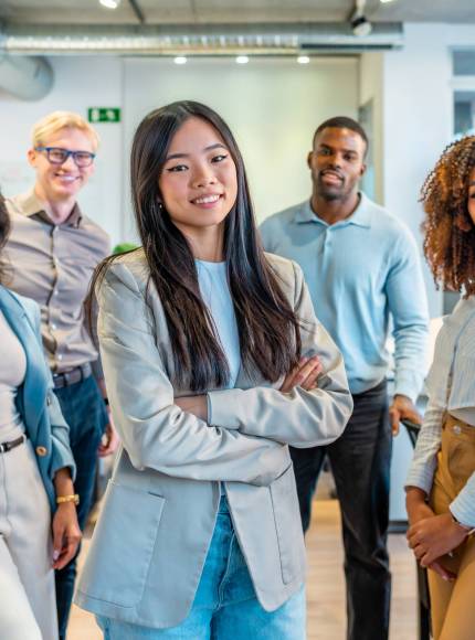 Diverse group of professionals posing together in a bright, modern coworking space, showcasing teamwork and collaboration